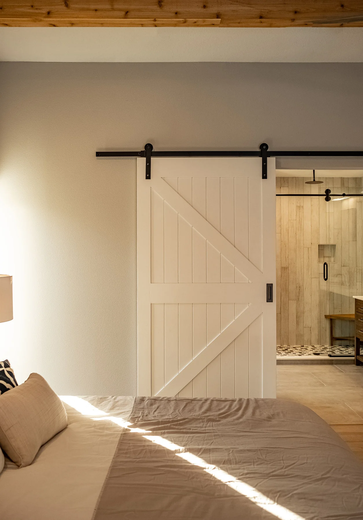 White sliding barn door opening onto a light wood bathroom interior.