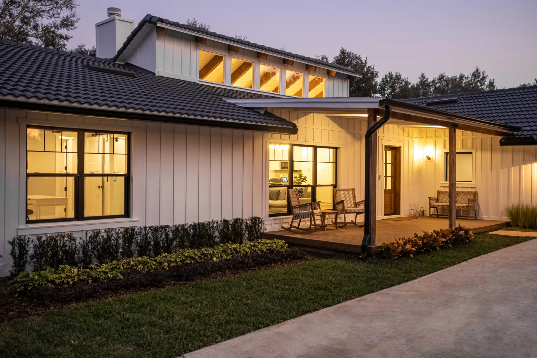 Modern single-story home exterior glowing through large windows at dusk.