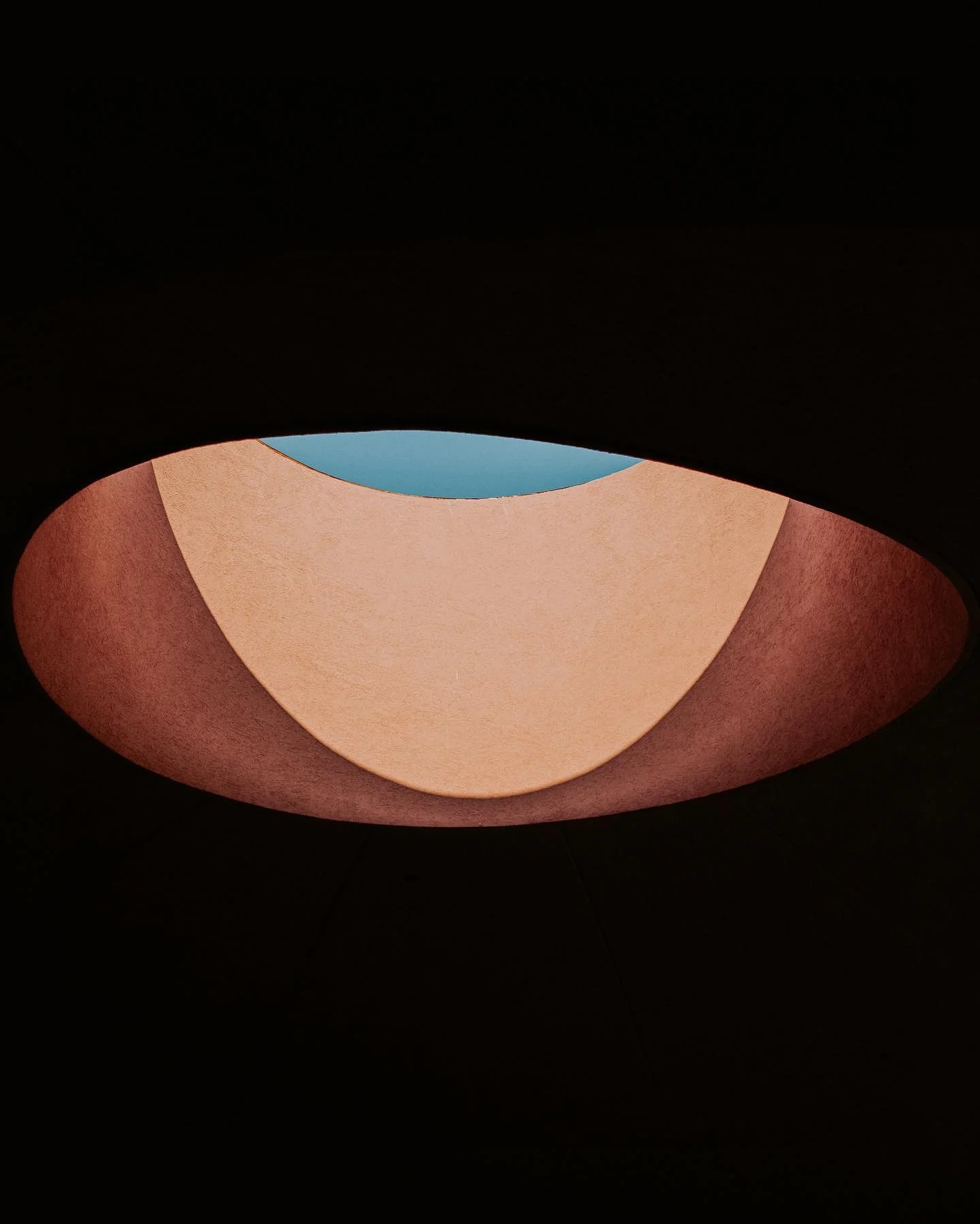 Circular skylight set inside a dark sculptural ceiling opening.