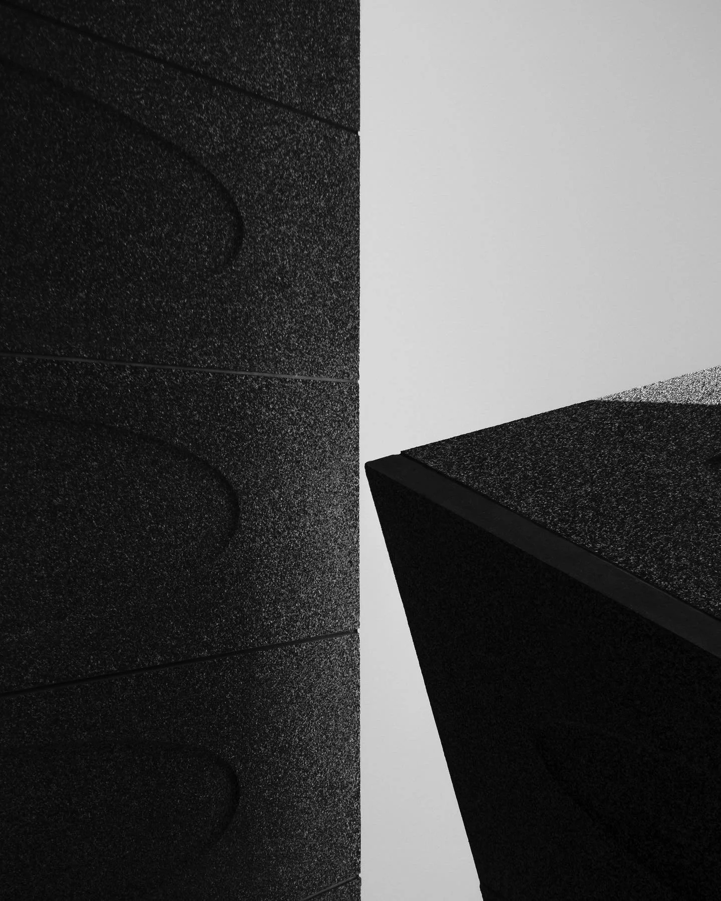 Abstract detail of a dark textured wall intersected by a crisp white plane.