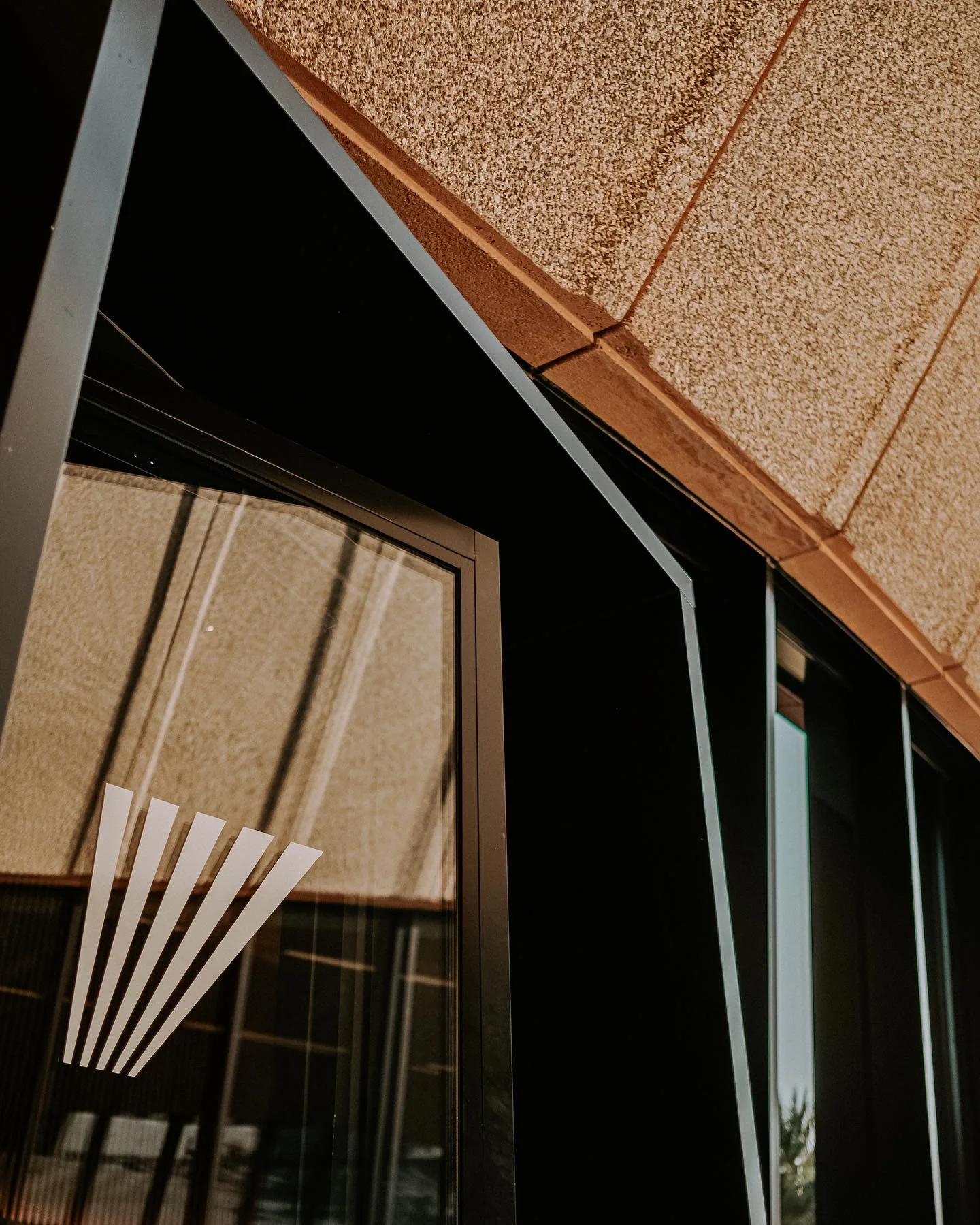 Angular ceiling and facade detail with warm wood and dark graphic panels.