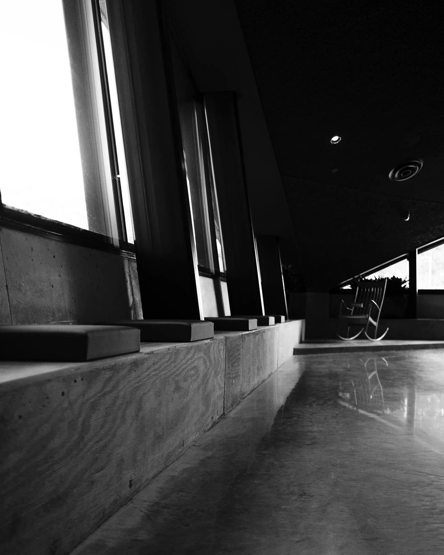 Black-and-white architectural interior with long counters, windows, and deep shadow.