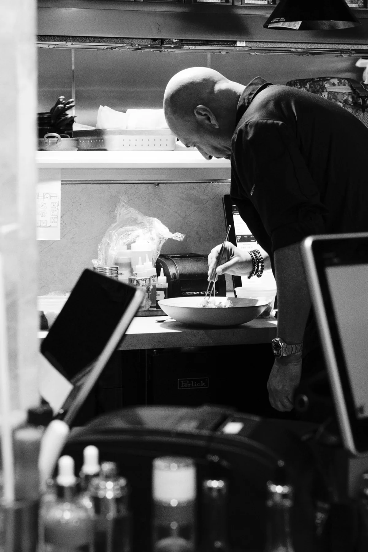 Chef plating a dish in the Chayote kitchen, photographed in black and white.