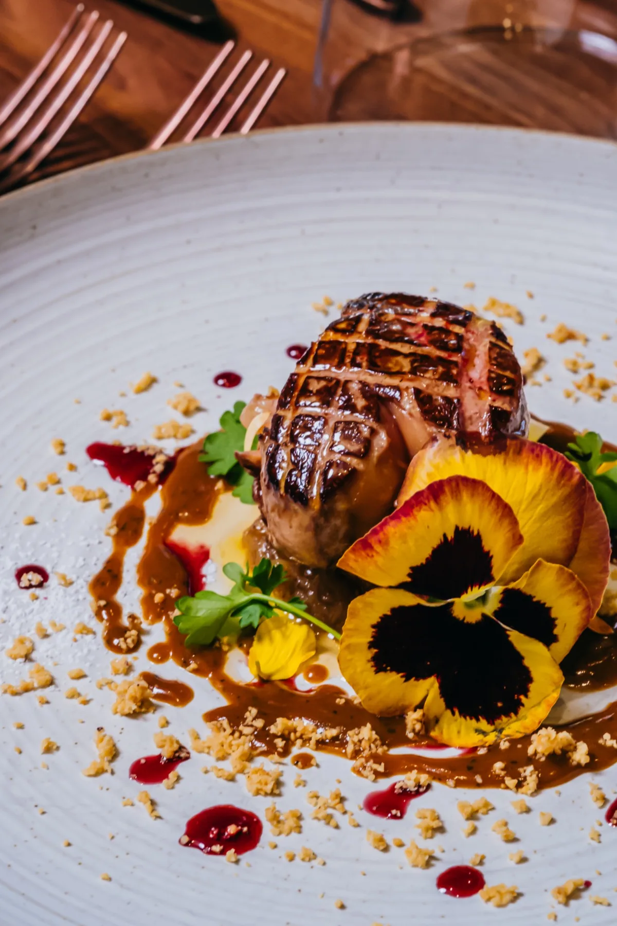 Seared foie gras plated with fruit and edible flowers.