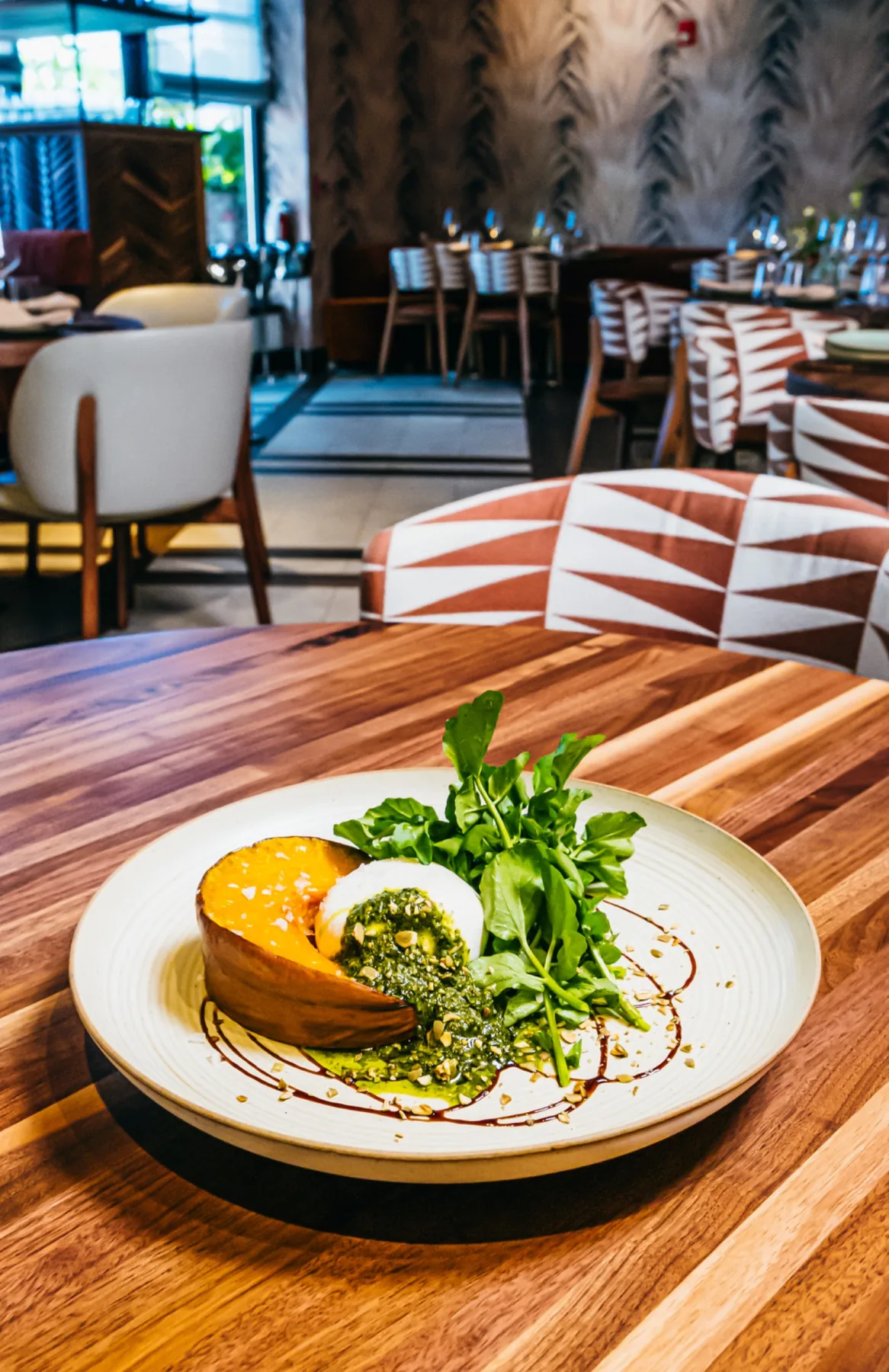 Roasted pumpkin dish with greens on a ceramic plate.
