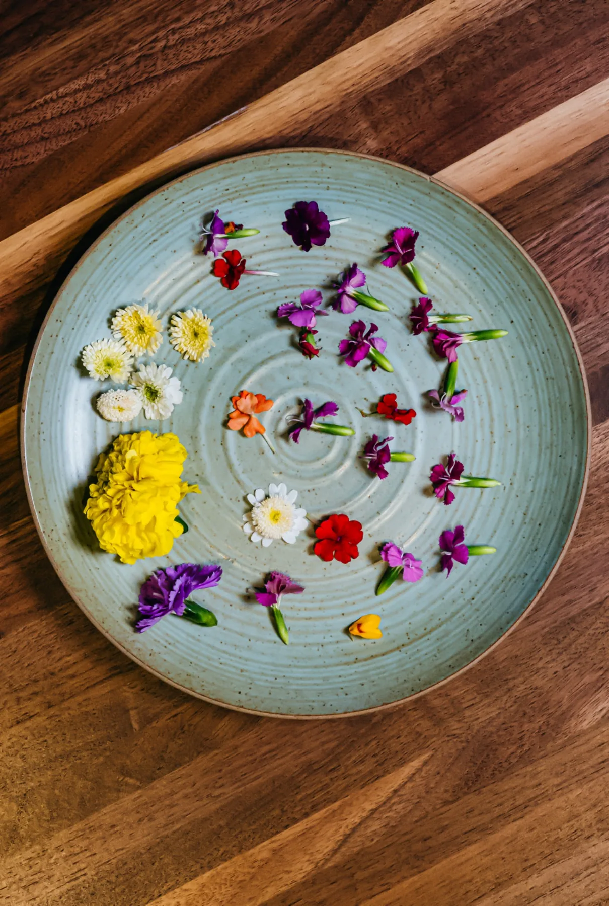 Pale blue ceramic plate scattered with edible flowers.