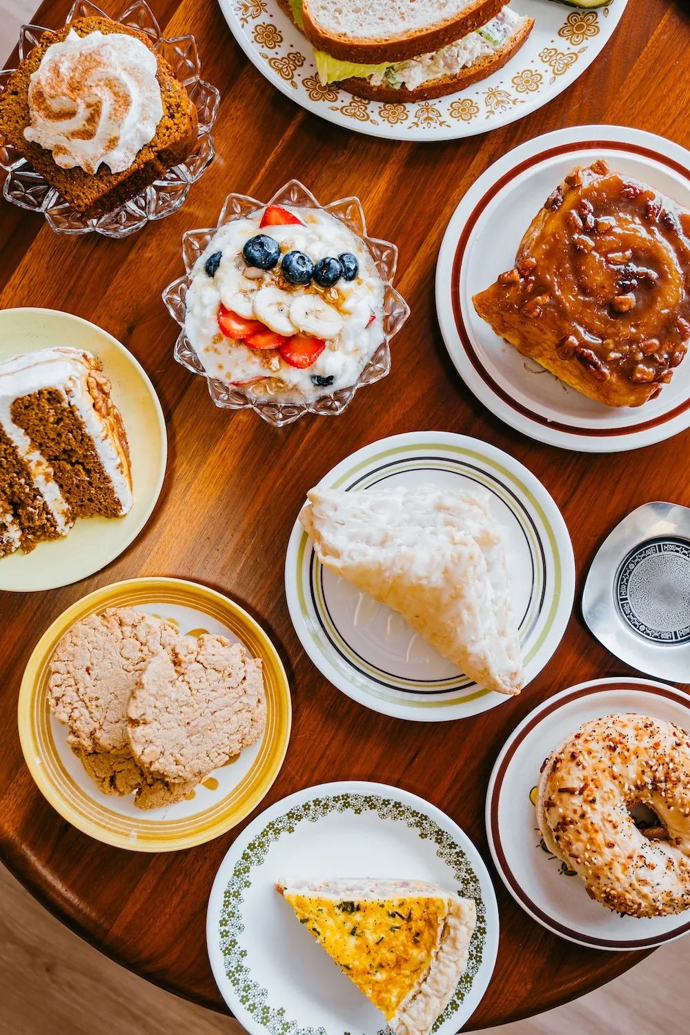 Assortment of cake slices and pastries arranged on a wood cafe table.