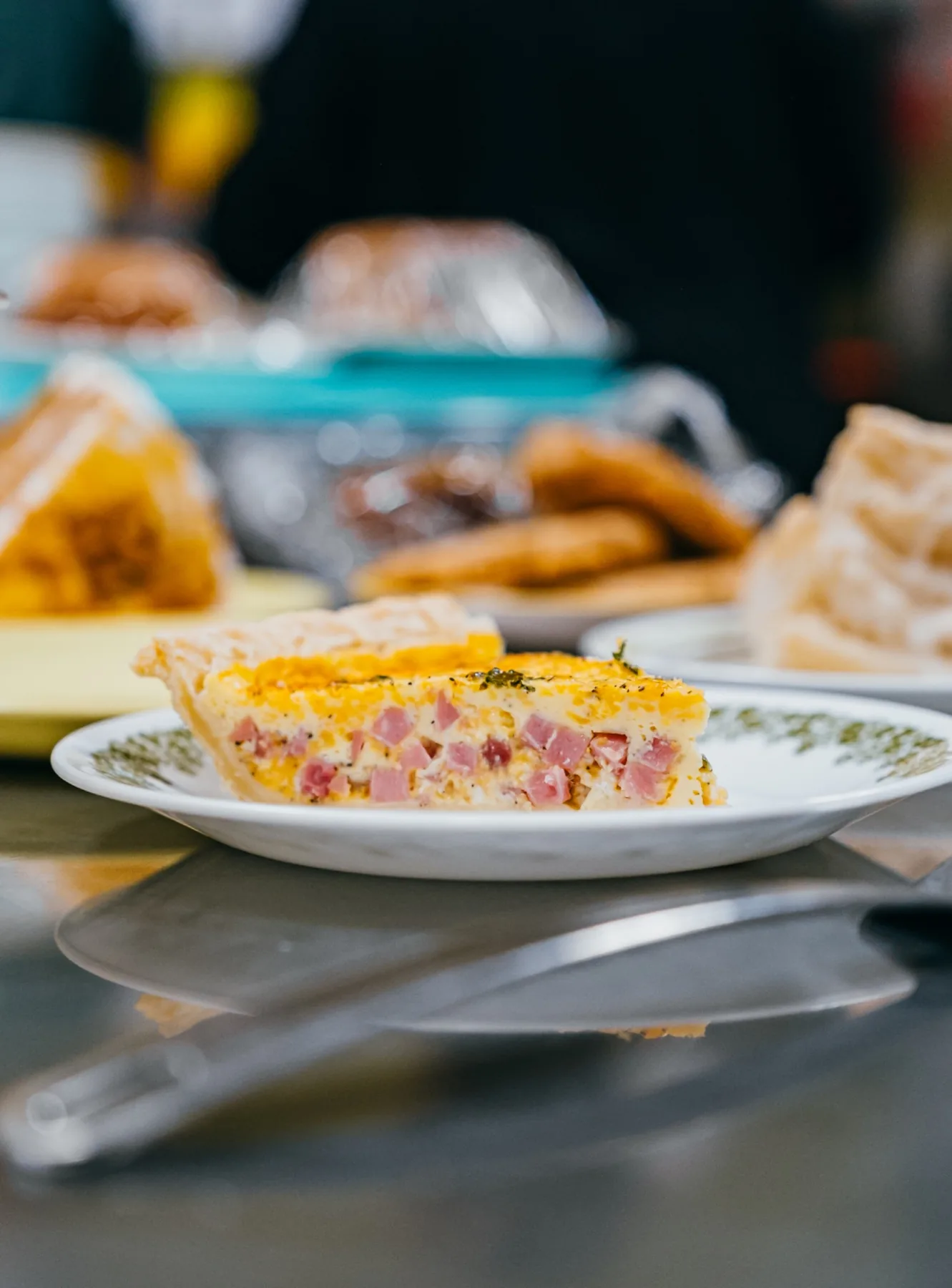 Savory quiche slice on a patterned plate at the cafe counter.