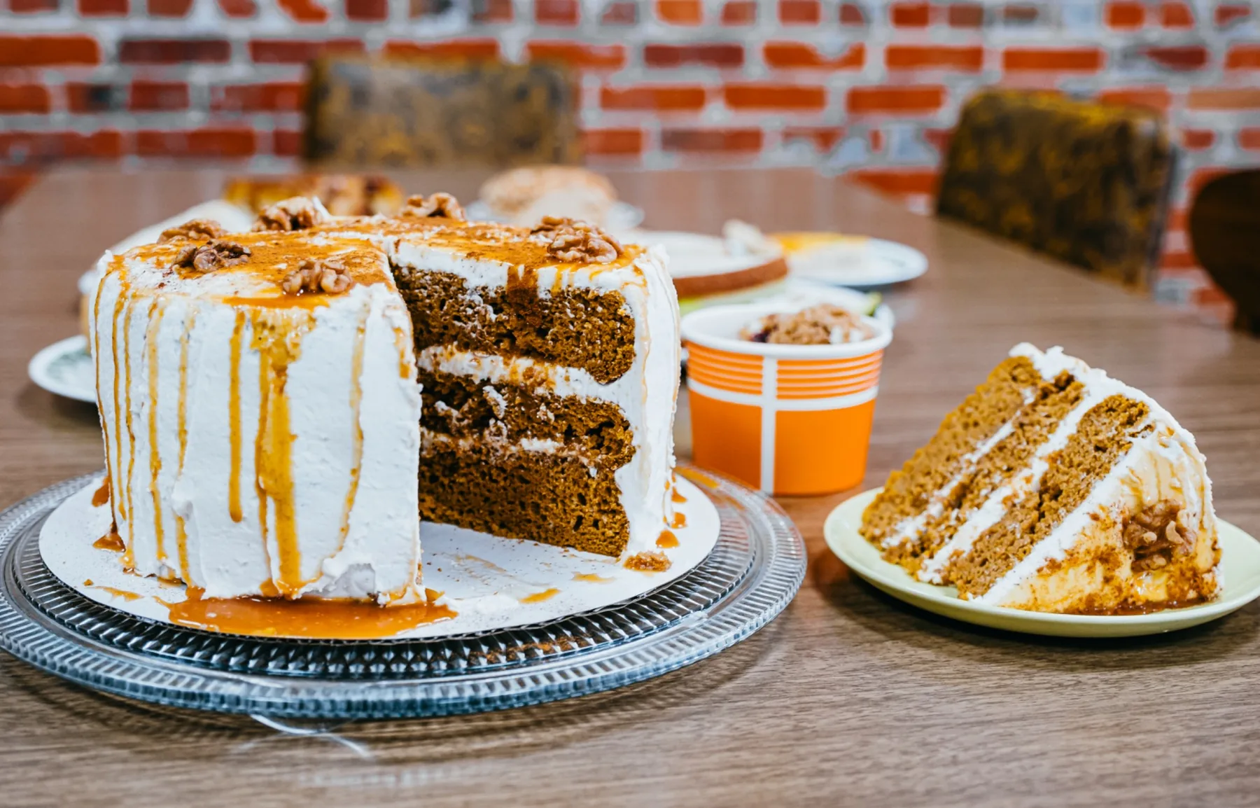 Caramel-drizzled layer cake and a plated slice on a diner table.