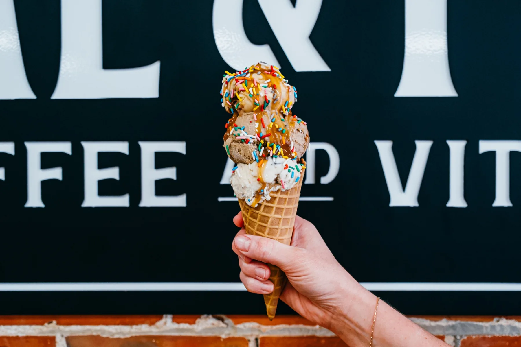 Ice cream cone held in front of the Coal and Feed storefront sign.