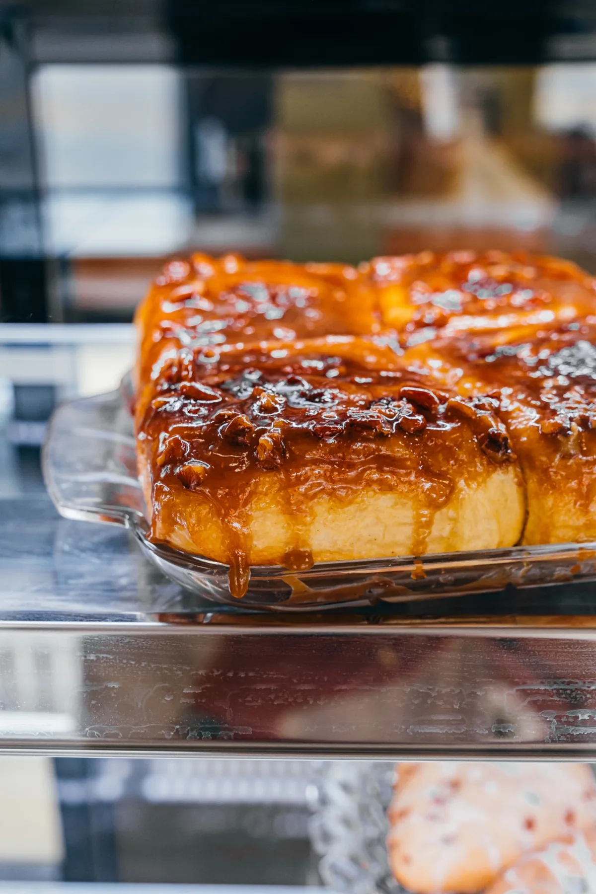 Glazed cinnamon roll on a glass cake stand.