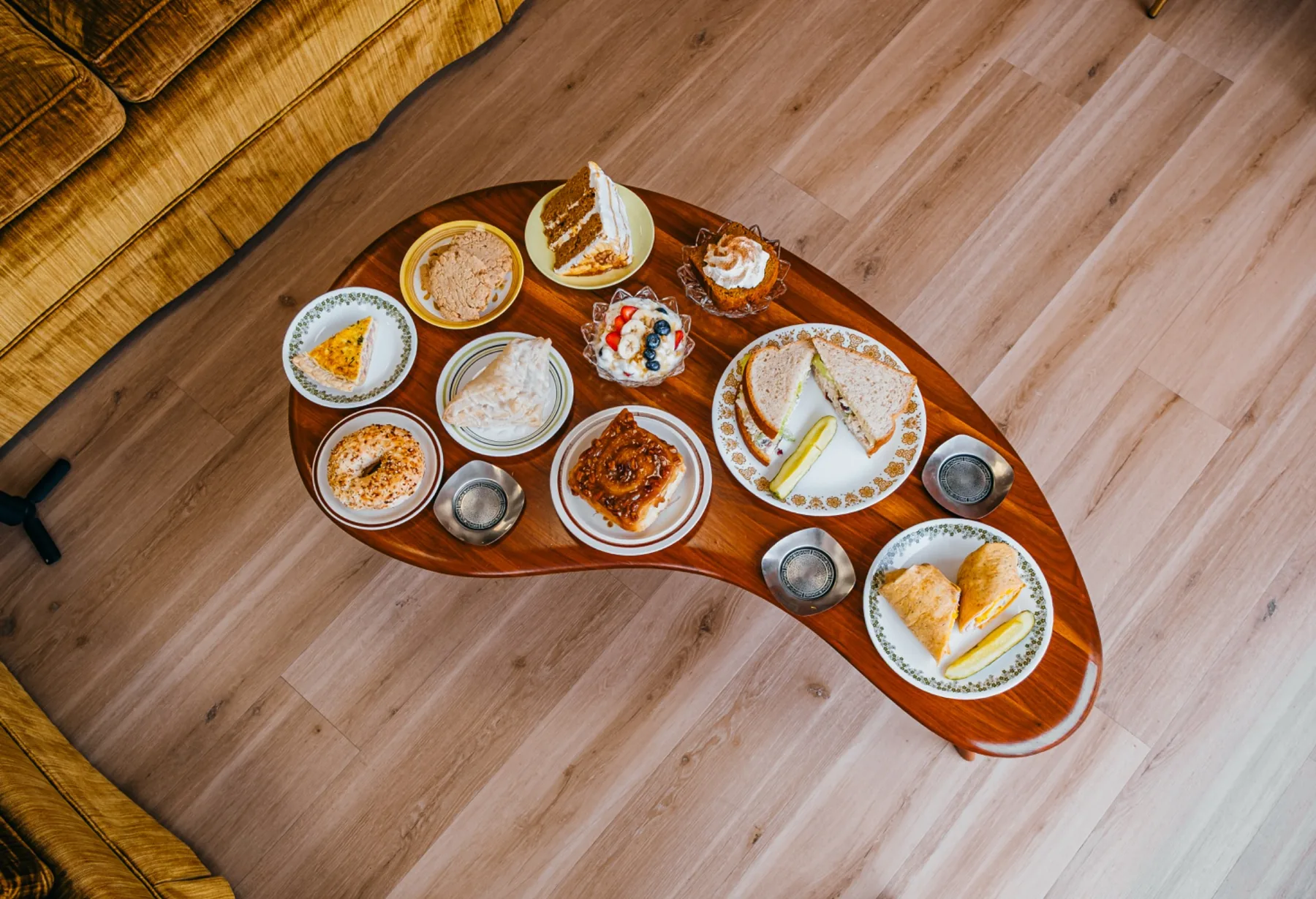 Wood cafe table arranged with a shared spread of pastries and small dishes.