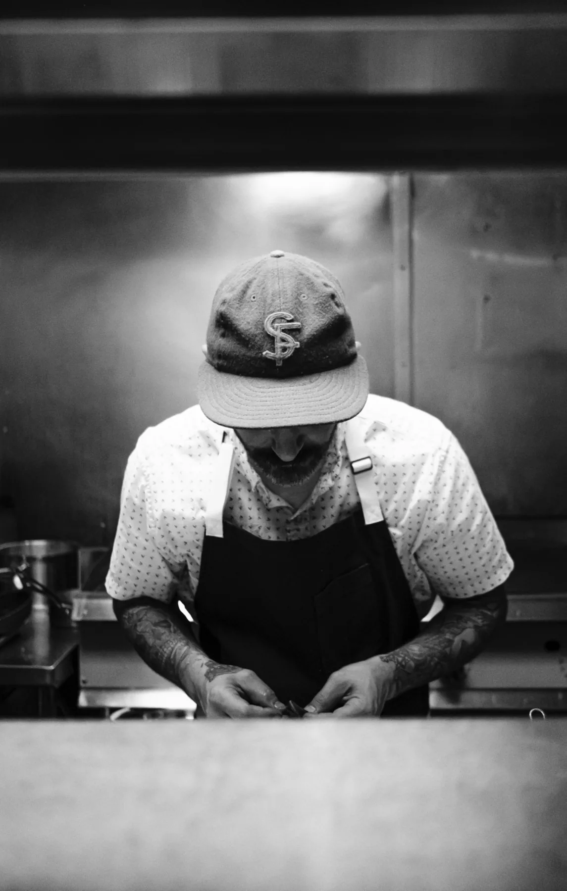 Chef in a dark apron preparing food in the Coro kitchen.