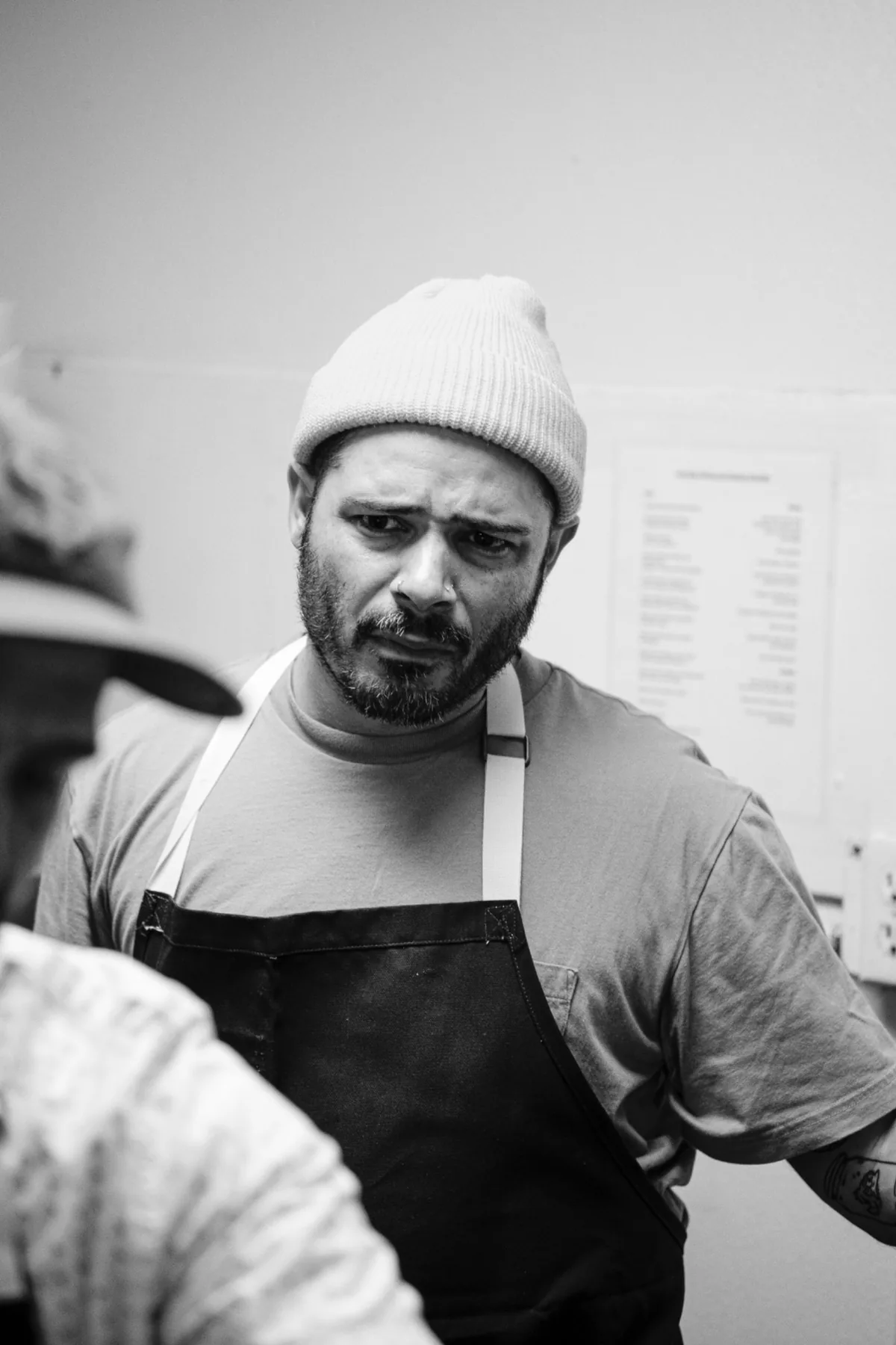 Black-and-white portrait of a chef in a knit cap and apron.