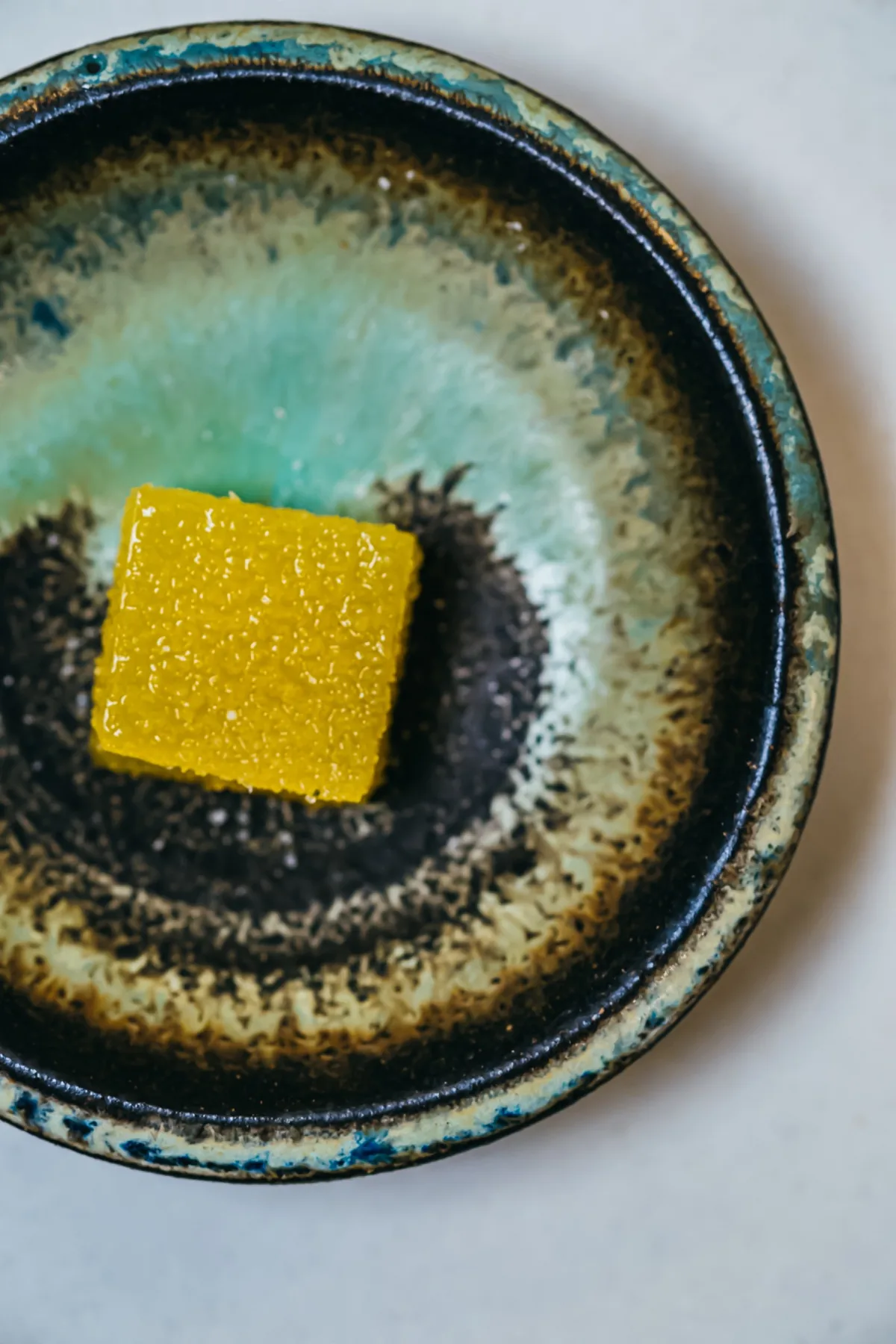 Golden dessert centered in a dark glazed ceramic bowl.