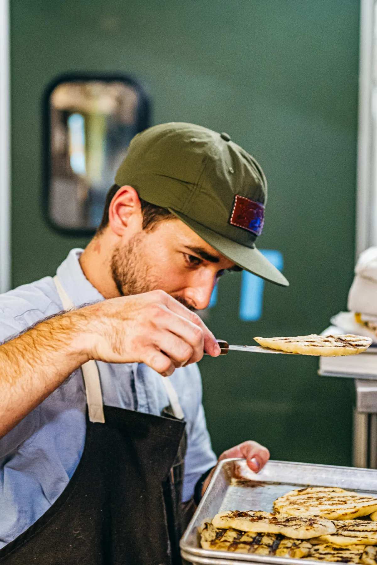 Cook in a cap carefully finishing a plate in the kitchen.