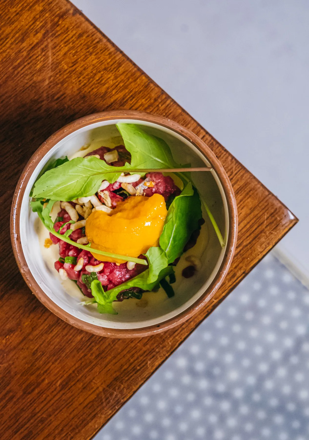 Overhead salad bowl with greens, grains, and a golden vegetable center.