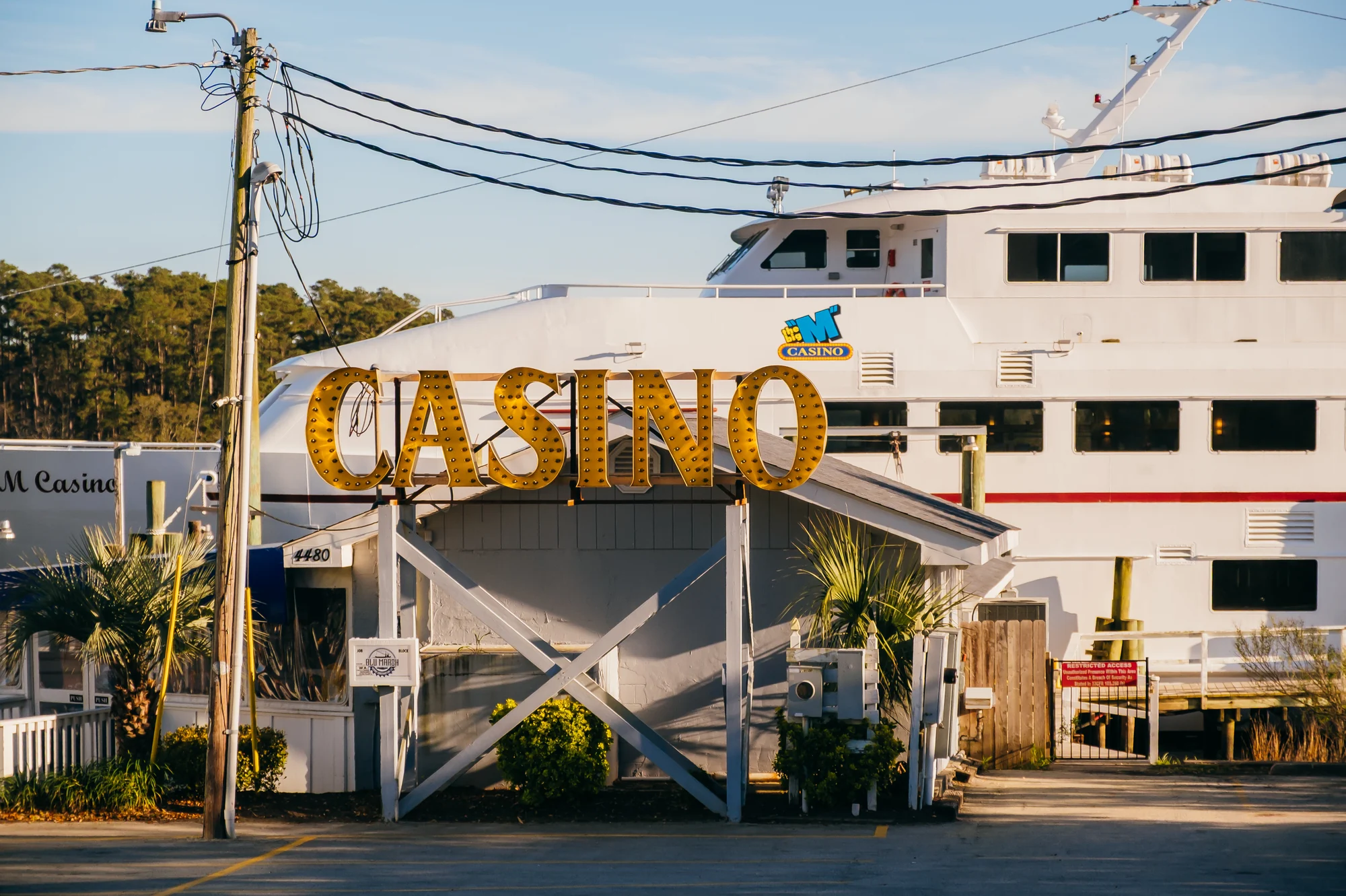 Golden marquee letters spelling CASINO in front of a large white ship with palm trees.