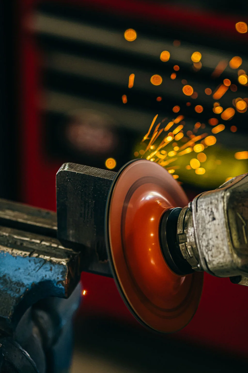 Orange sparks flying from a rotating bench grinder in the metal shop.