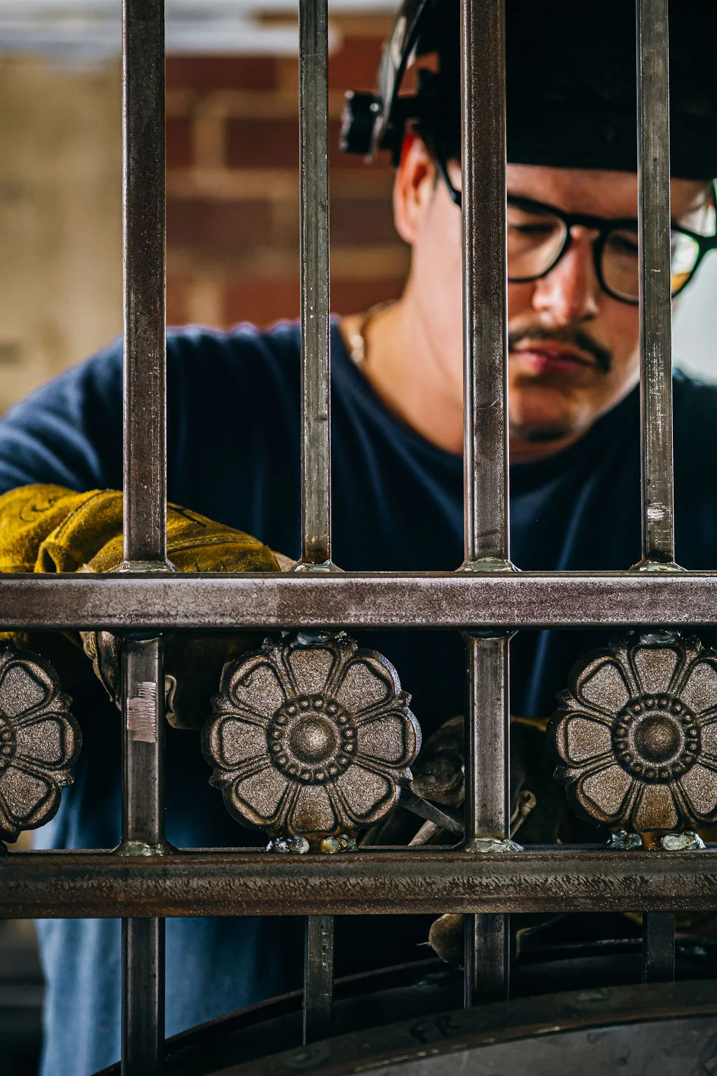 Portrait of a metalworker framed through a decorative steel gate.