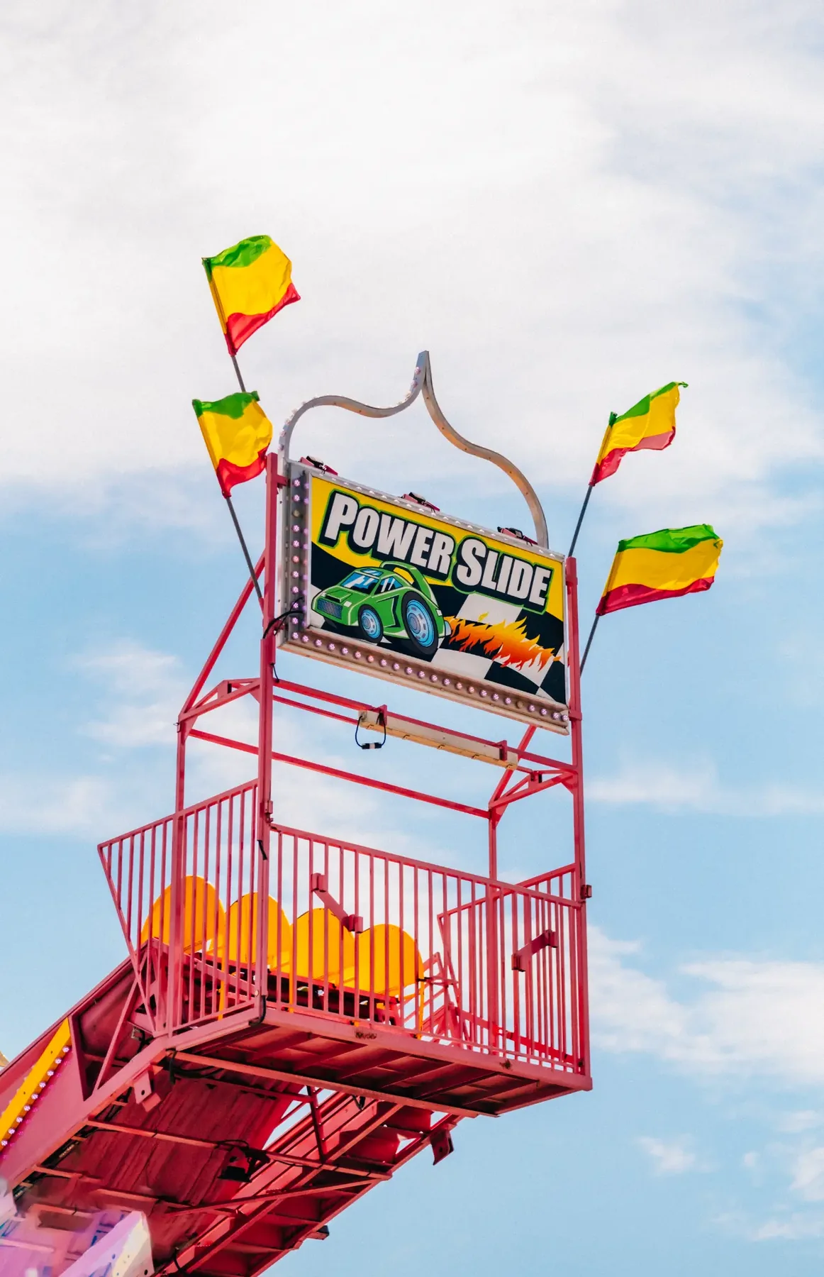 Power Slide carnival sign framed by bright flags.