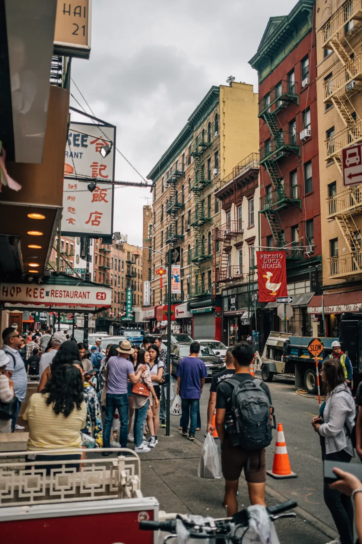 Crowded Chinatown street with market awnings and signs.