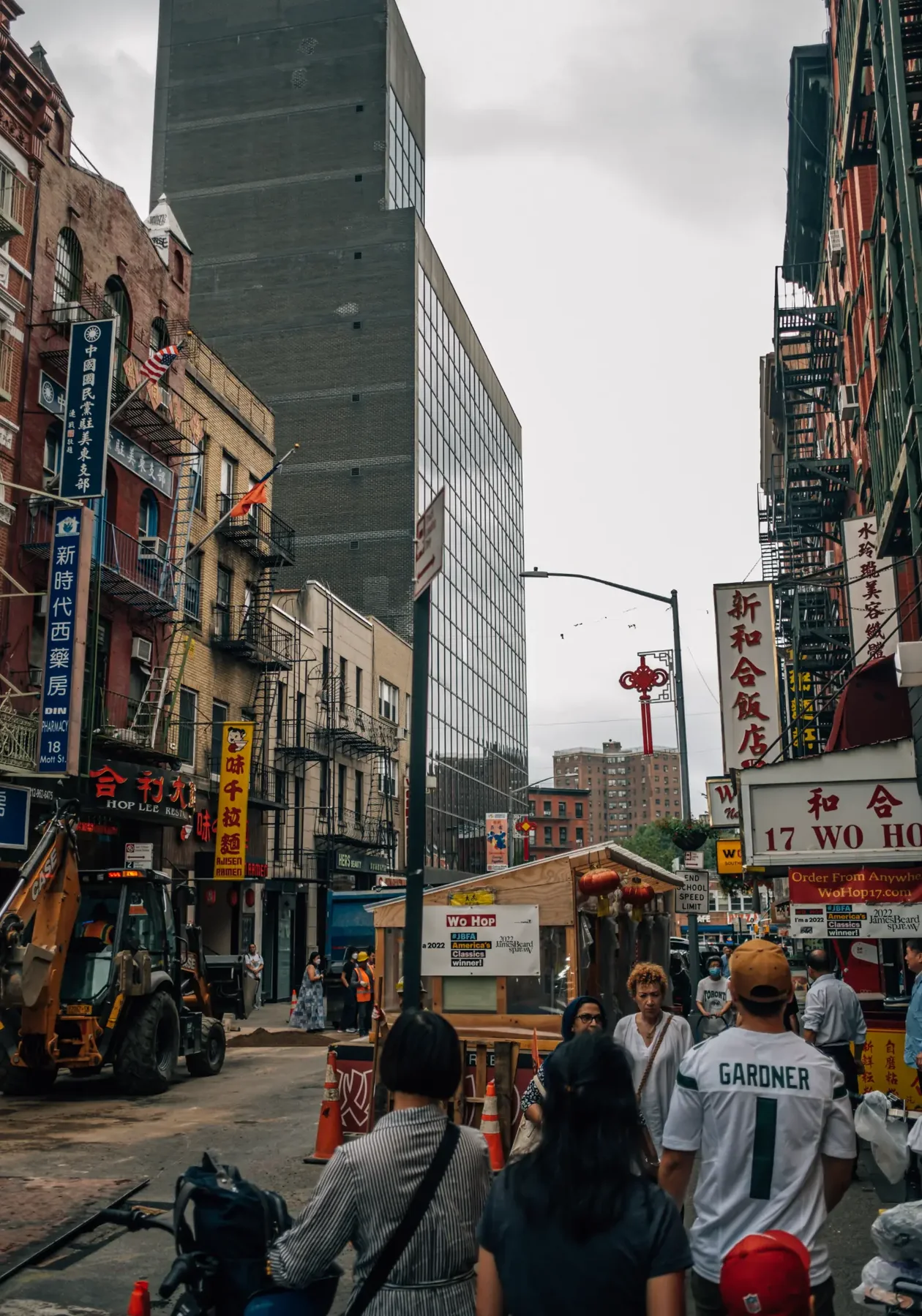 New York City street canyon with pedestrians beneath a cloudy sky.