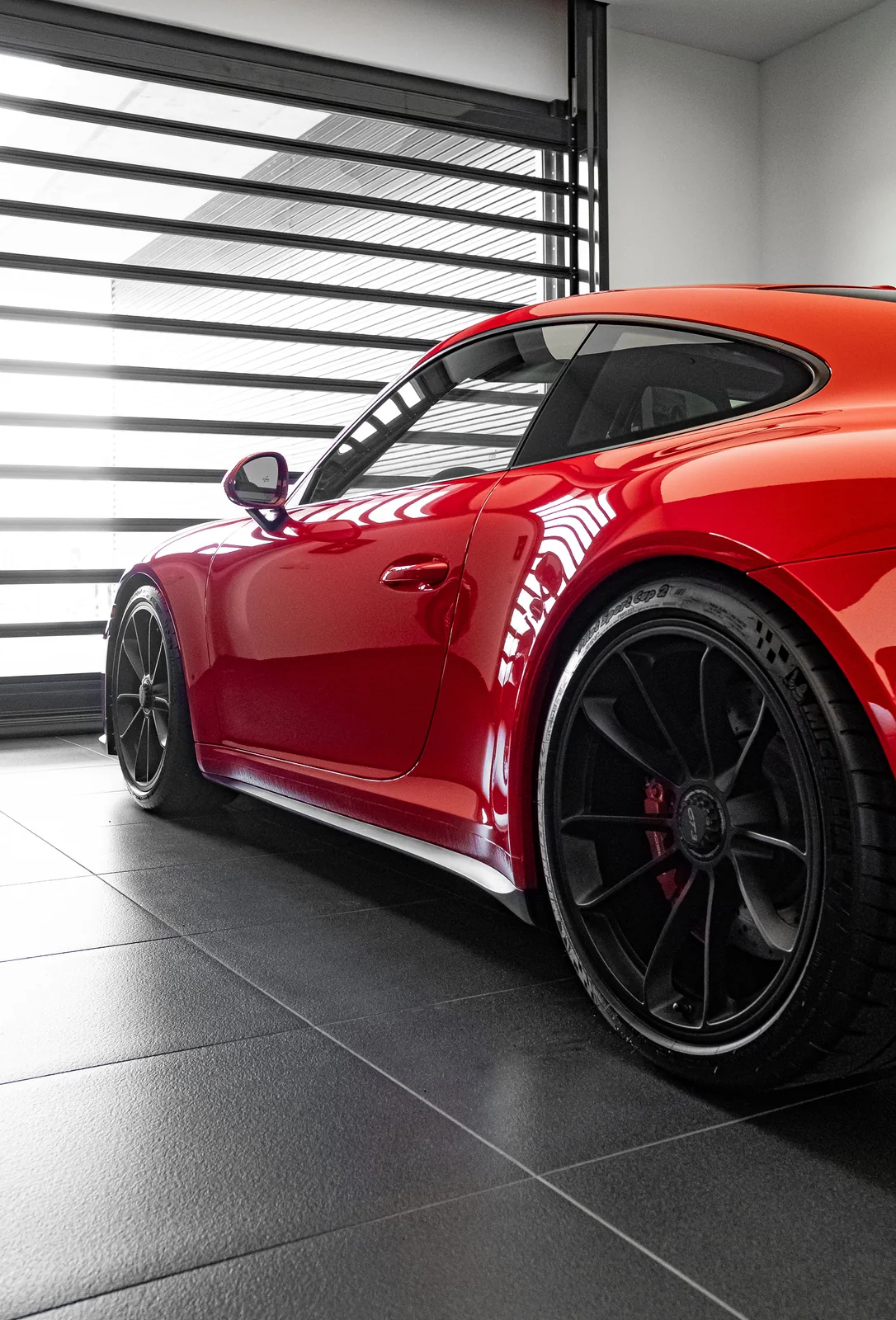 Low angle of a red Porsche 911 in a dark showroom.