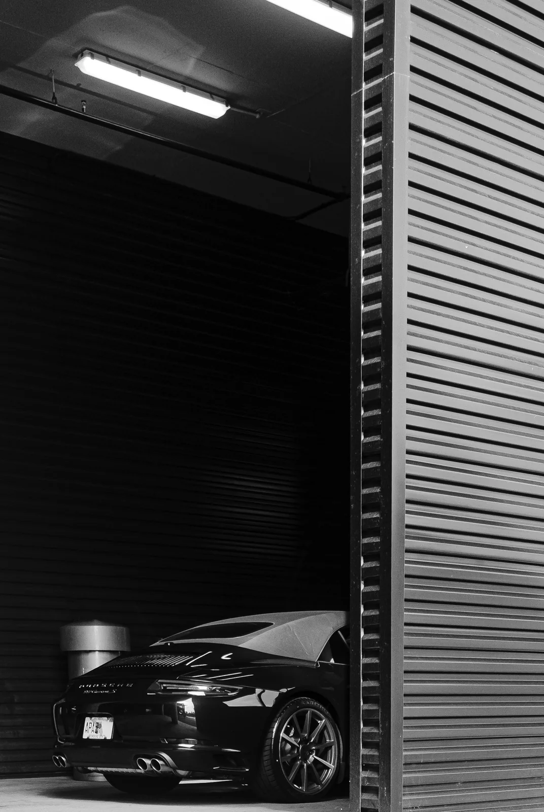 Black Porsche sports car positioned beneath dealership lights.