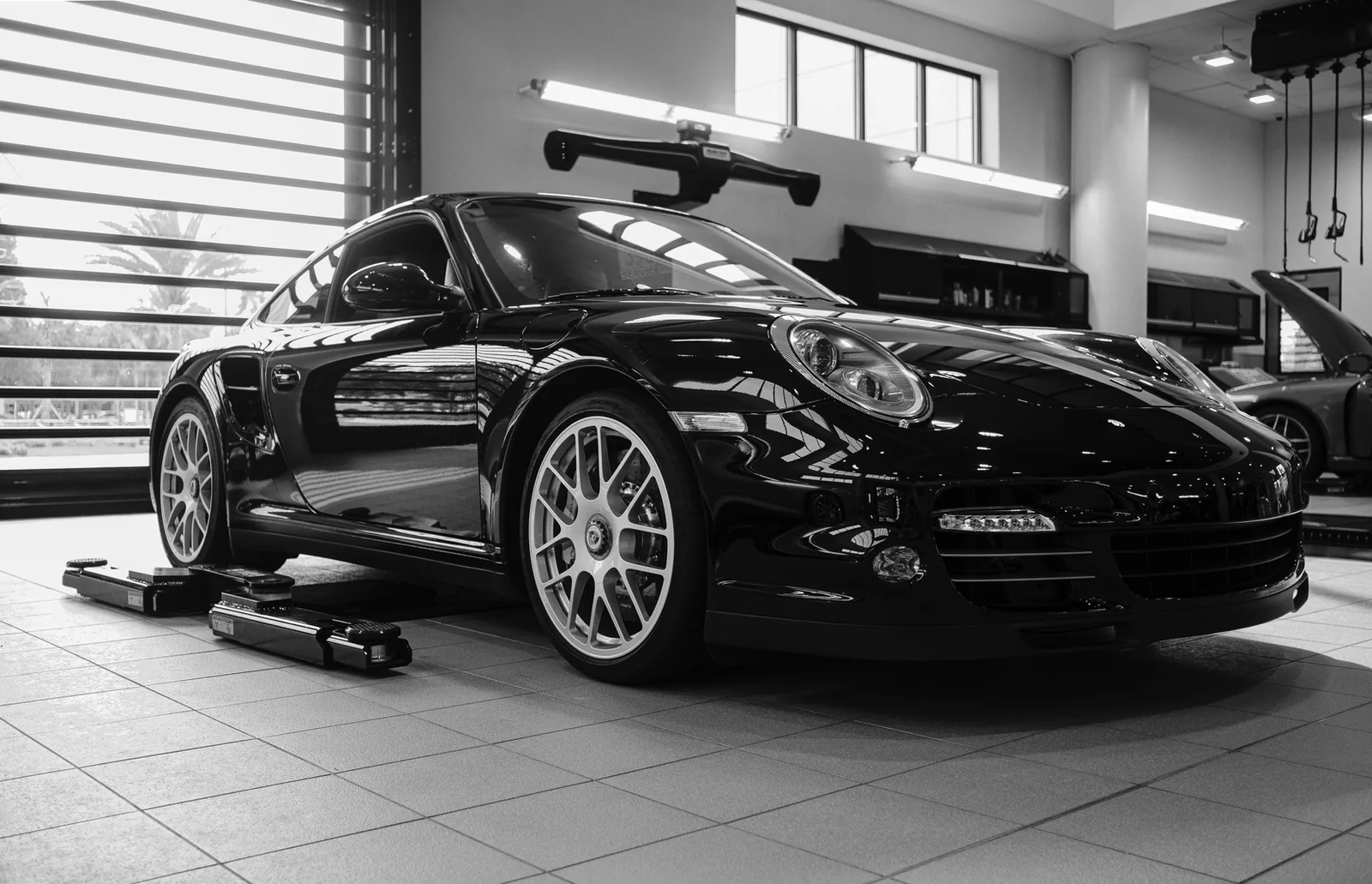 Bright Porsche service bay with lifts and tool cabinets.