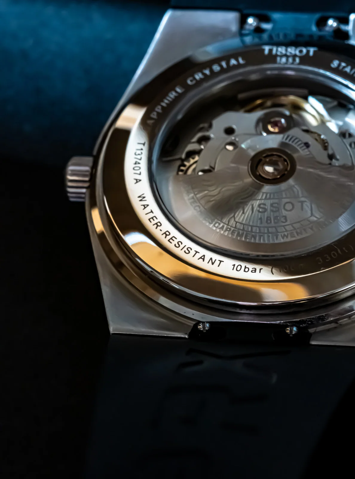 Close detail of the Tissot watch case back and visible mechanical movement.